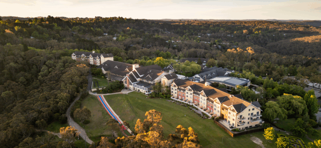 Aerial view of Fairmont Resort Blue Mountains surrounded by bushland, with resort buildings, gardens and outdoor recreation areas.